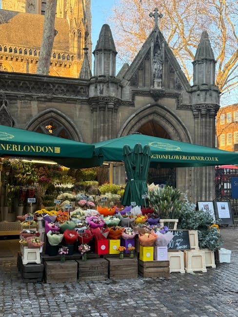 An outdoor flower stall at the Benedictine church in Kensington, featuring a vibrant display of fresh floral bouquets arranged in colorful wrapping paper and placed on wooden crates. The bouquets incl